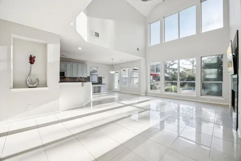 a large white kitchen with stainless steel appliances kitchen island granite countertop a large window and cabinets