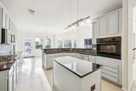 a kitchen with stainless steel appliances granite countertop a stove a sink and a microwave