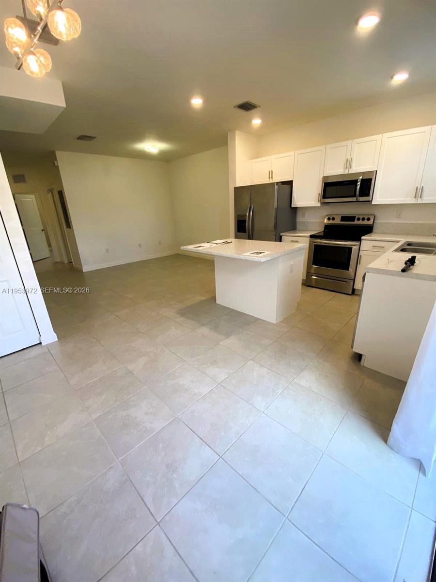 18220 Southwest 148th Road Miami, FL 33187 - Photo 8 of 23 a large kitchen with a large counter top and stainless steel appliances