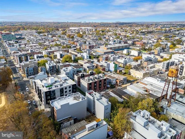 an aerial view of a city with lots of residential buildings ocean and mountain view in back