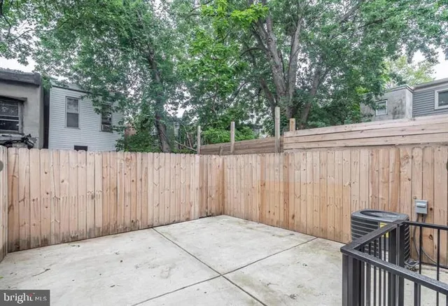a view of backyard with wooden fence and large trees