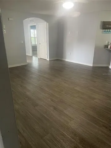a view of an empty room with wooden floor and a mirror