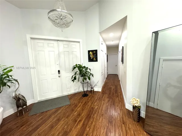 a view of a hallway with wooden floor and a chandelier