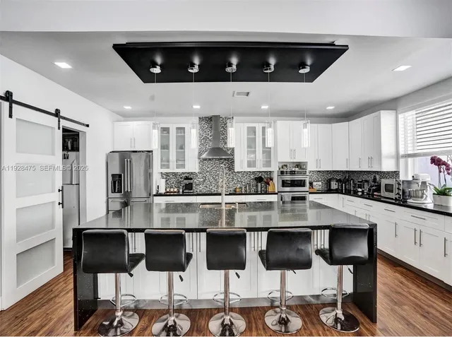 a kitchen with stainless steel appliances granite countertop a stove top oven a refrigerator and white cabinets