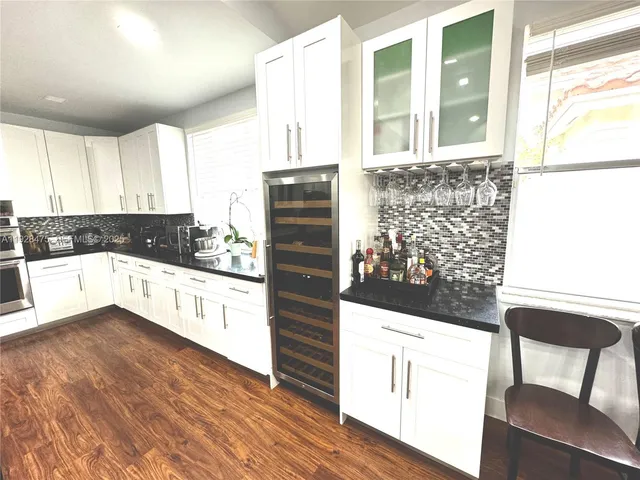 a kitchen with granite countertop a stove a sink and white cabinets with wooden floor