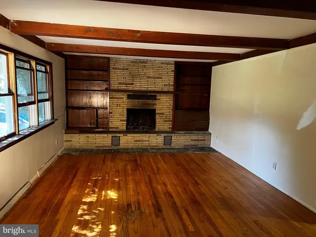 a view of empty room with wooden floor and fireplace