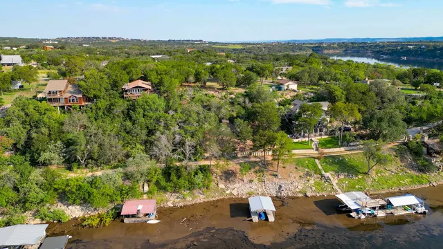 an aerial view of residential houses with outdoor space and trees all around