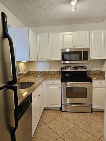 a kitchen with granite countertop a stove sink and cabinets