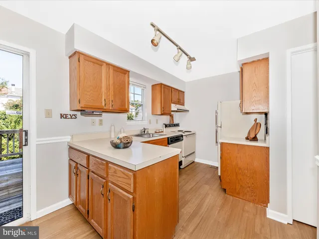 a kitchen with stainless steel appliances a sink stove and wooden floor