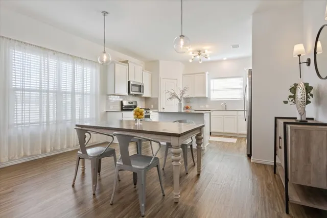 a dining room with stainless steel appliances a table chairs and chandelier