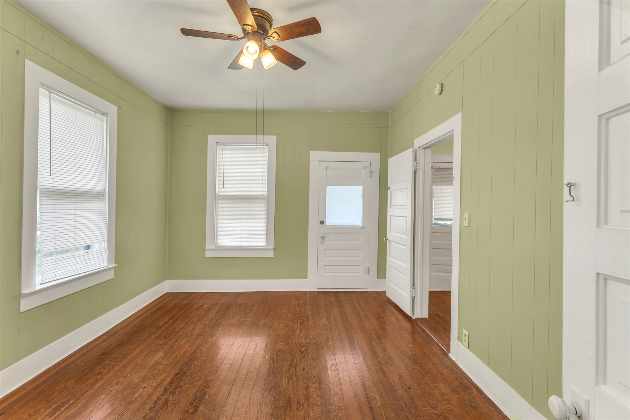 1002 Washburn Street Taylor, TX 76574 - Photo 23 of 29 Room featuring hardwood floors, two windows with blinds, and light green walls