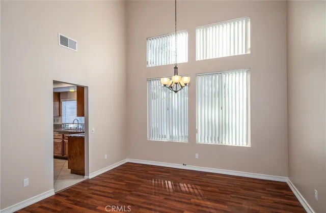 an empty room with wooden floor cabinet and windows