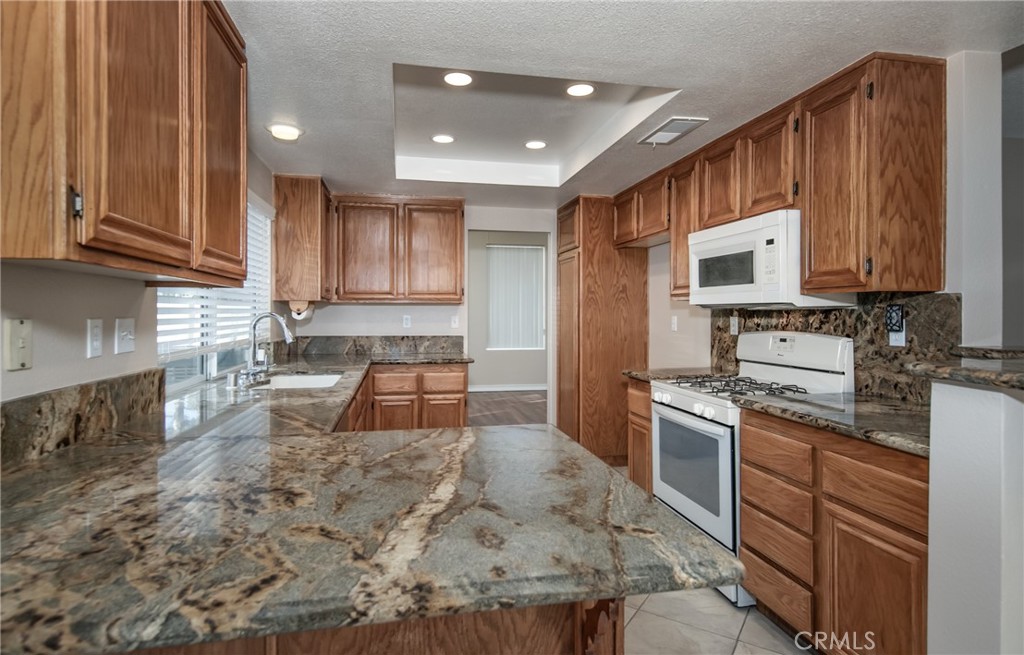 31255 Slate Street Mentone, CA 92359 - Photo 6 of 28 a kitchen with stainless steel appliances granite countertop a stove a sink dishwasher and a refrigerator with wooden cabinets