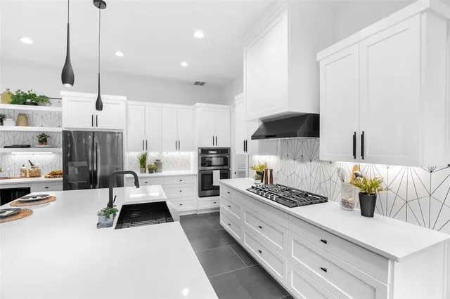 a kitchen with kitchen island stainless steel appliances a sink a counter top space stove and cabinets