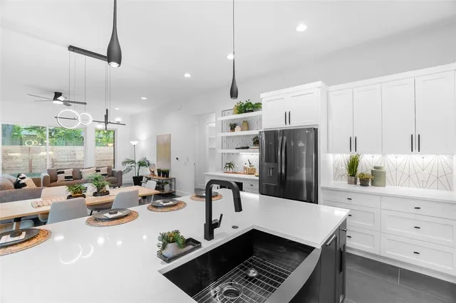 a kitchen with stainless steel appliances kitchen island granite countertop a refrigerator a stove and white cabinets with wooden floor