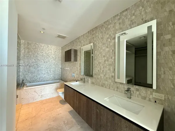 a bathroom with a bathtub a double vanity sink and mirror