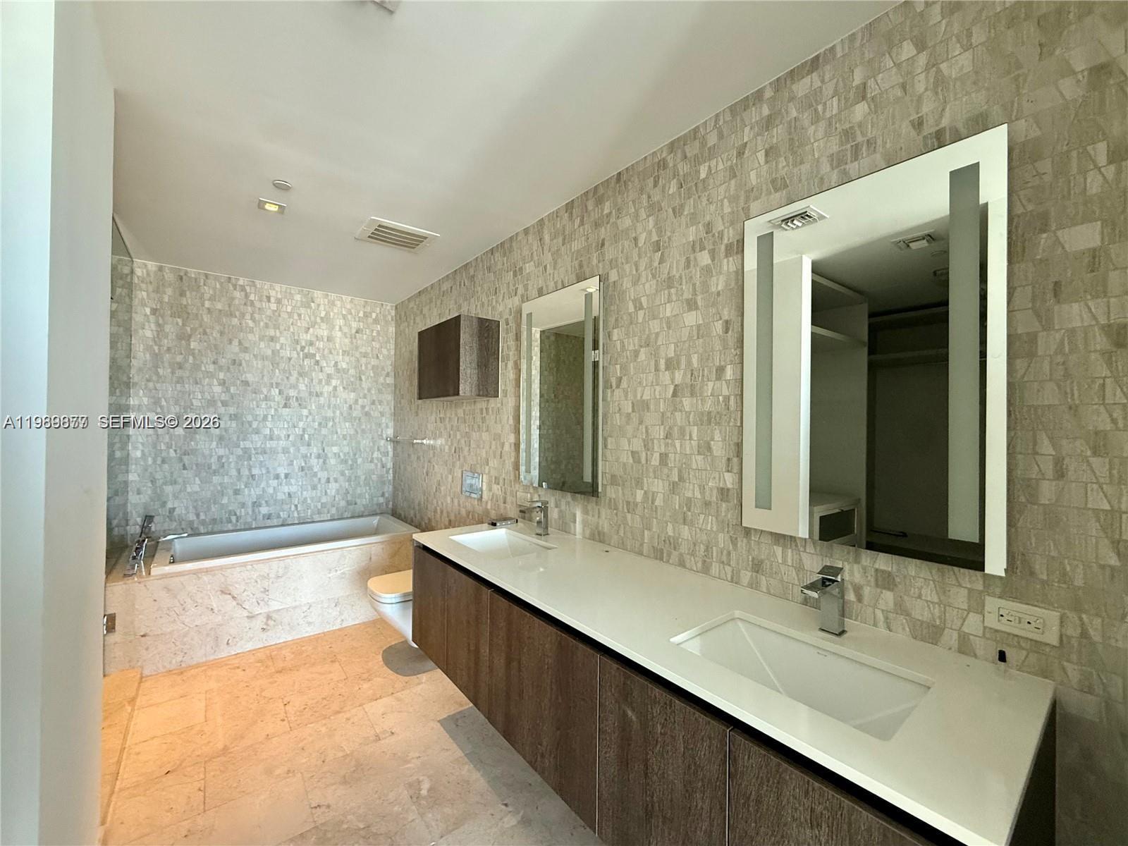 88 Southwest 7th Street, Unit 1808 Miami, FL 33130 - Photo 8 of 9 a bathroom with a bathtub a double vanity sink and mirror