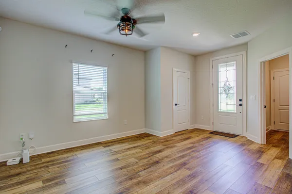a view of an empty room with wooden floor and a window