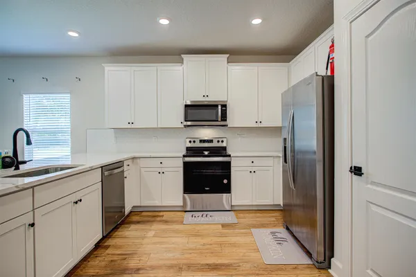 a kitchen with a refrigerator sink and white cabinets