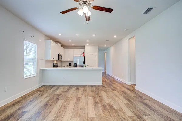 a view of kitchen center island wooden floor and ceiling fan