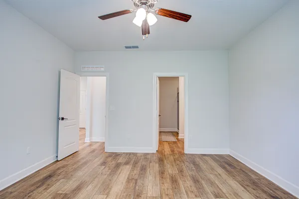 an empty room with wooden floor fan and windows