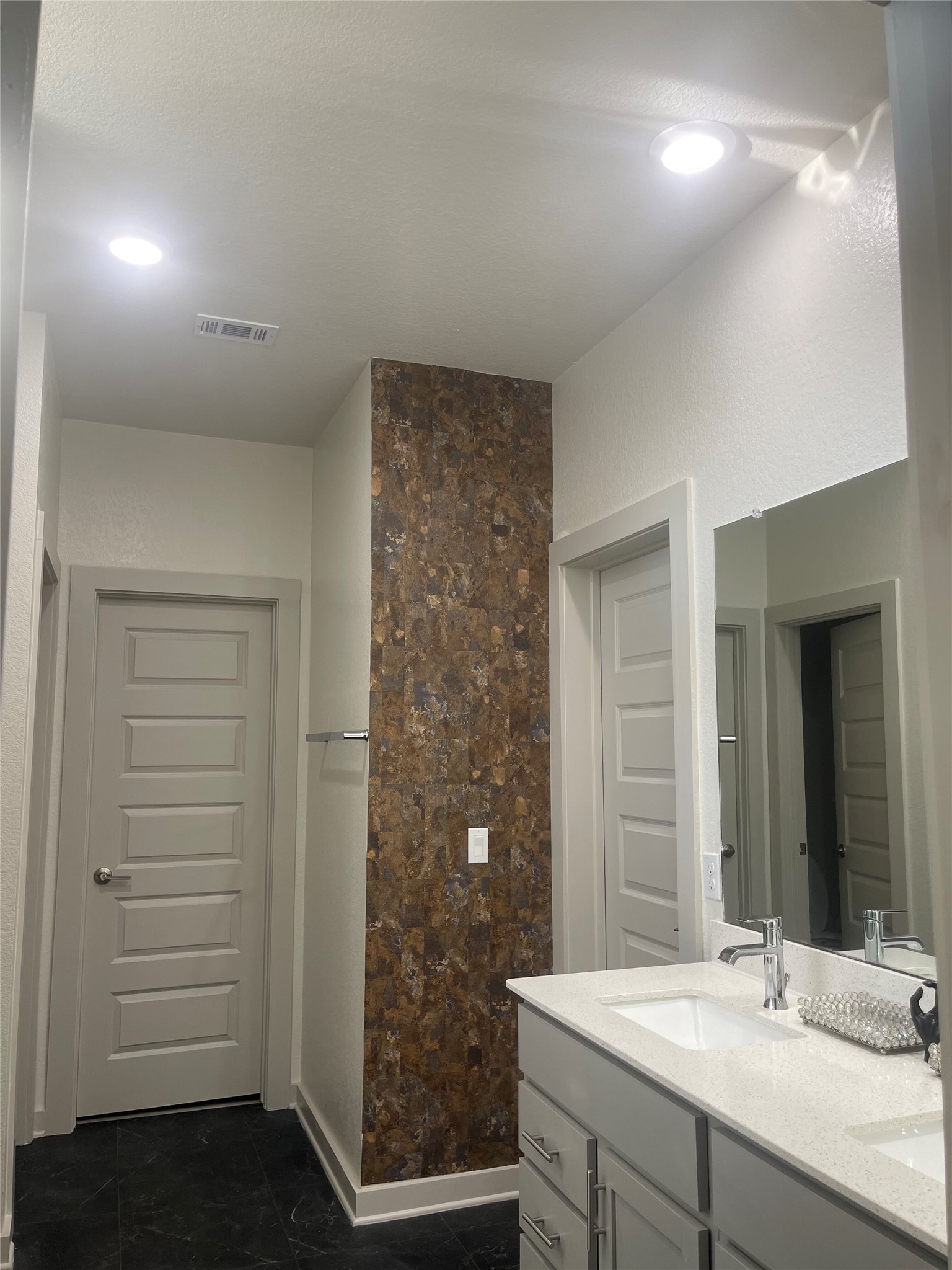 145 Merrick Road Georgetown, TX 78628 - Photo 17 of 32 A stylish vanity with stone counters and modern fixtures stands out against dark tile floors.