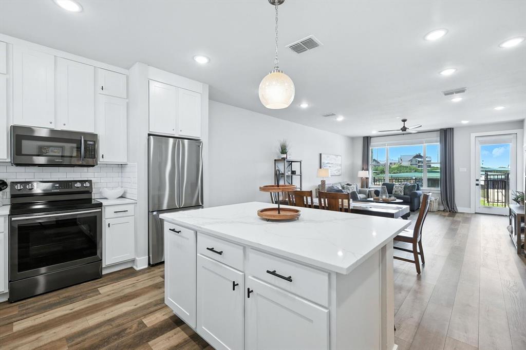 3412 Scenic Point Road, Unit 104 Graford, TX 76449 - Photo 7 of 35 a kitchen with a stove a refrigerator and a dining table with wooden floor