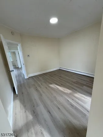 a view of an empty room with wooden floor and stairs