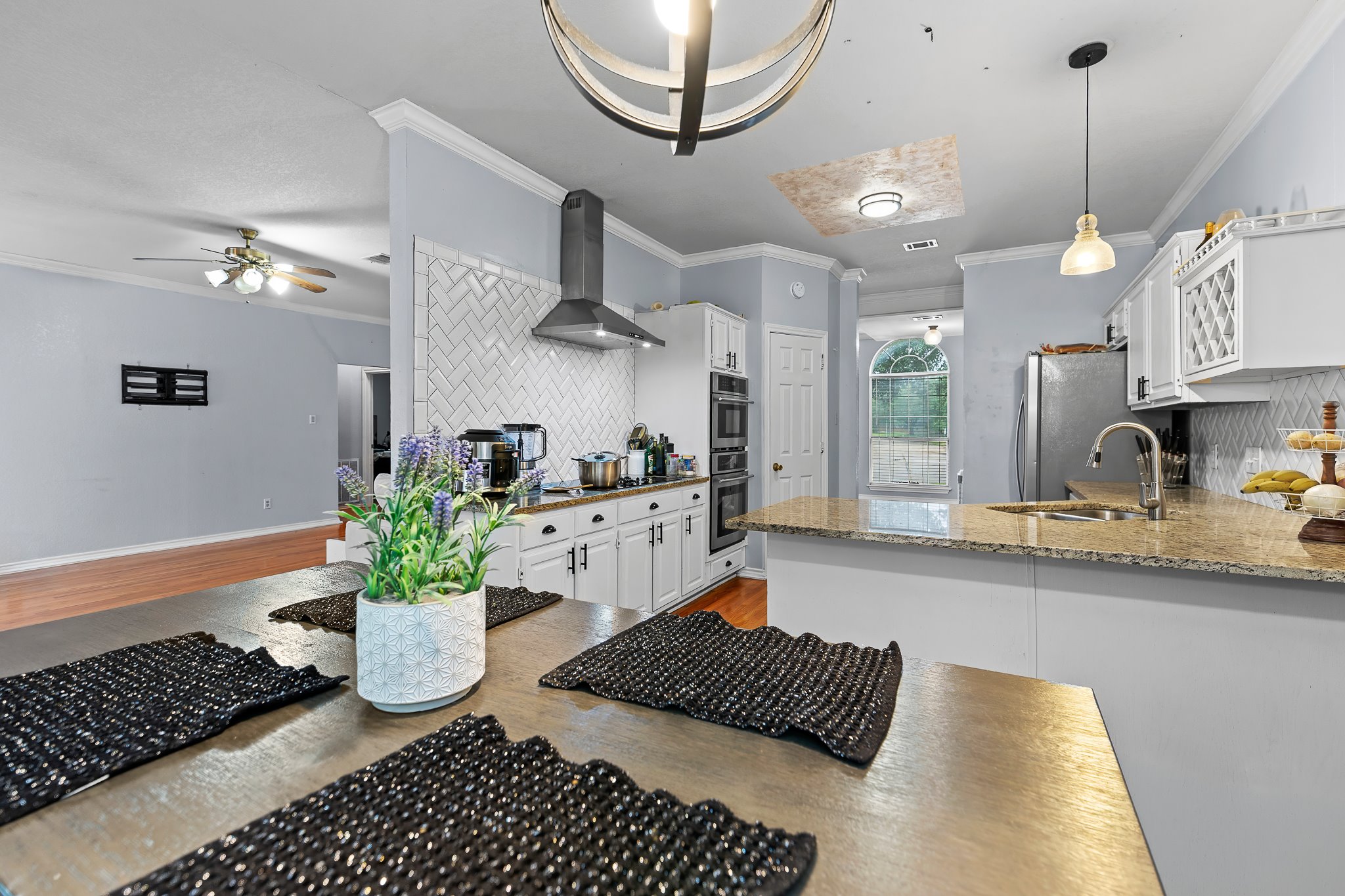 11737 Rydalwater Lane Austin, TX 78754 - Photo 32 of 40 Modern kitchen featuring white cabinetry, granite countertops, a herringbone tile backsplash, stainless steel appliances, and a built-in double oven