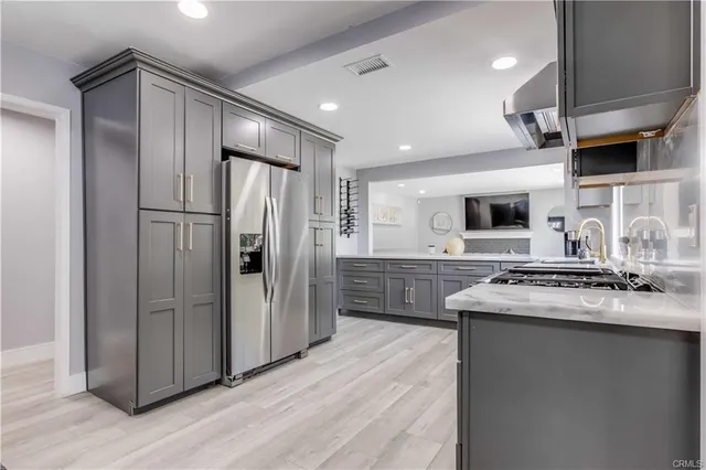 a kitchen with stainless steel appliances granite countertop a refrigerator a sink dishwasher a stove and a refrigerator with wooden floor