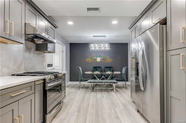 a kitchen with stainless steel appliances granite countertop a stove top oven a sink and chairs