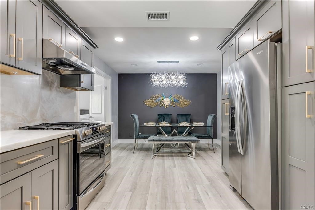 10664 Morning Glory Avenue Fountain Valley, CA 92708 - Photo 9 of 31 a kitchen with stainless steel appliances granite countertop a stove top oven a sink and chairs