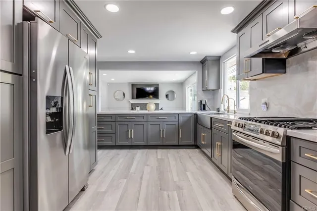 a kitchen with stainless steel appliances a refrigerator a sink dishwasher a stove and white cabinets