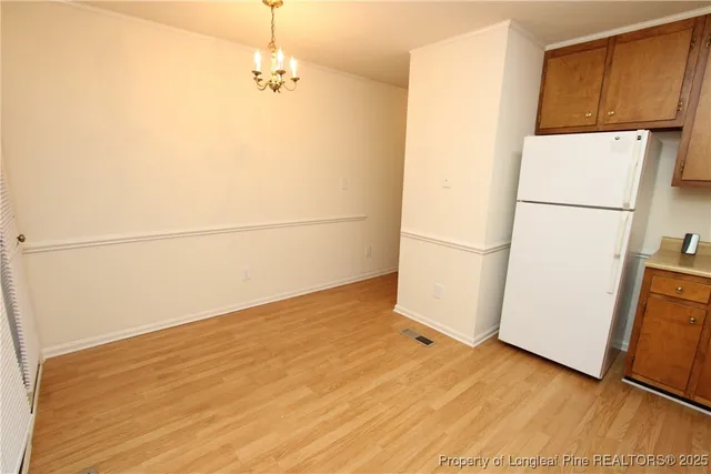 a view of a refrigerator in kitchen and an empty room