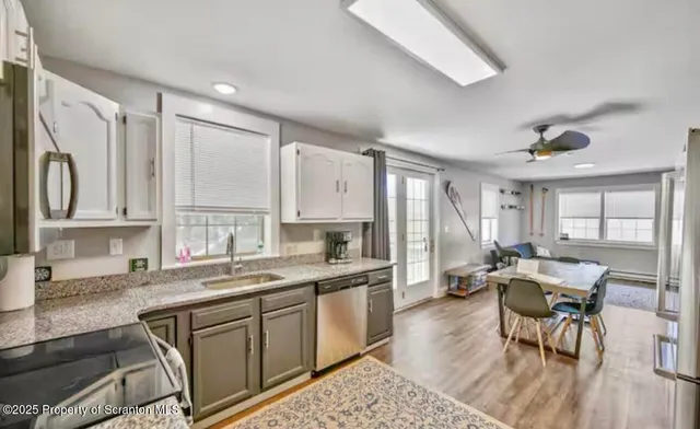 a kitchen with stainless steel appliances granite countertop white cabinets sink and window