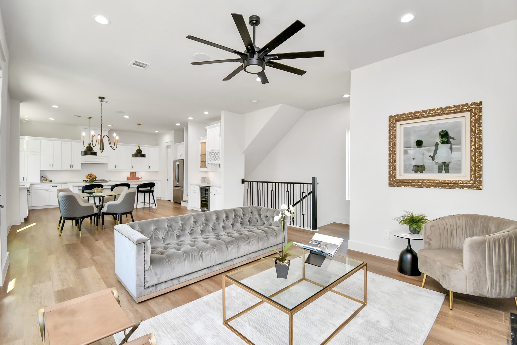 2512 Gray Street Houston, TX 77003 - Photo 12 of 46 This spacious open-concept living area features a modern kitchen with white cabinetry, a cozy dining space, and a stylish living room with a gray tufted sofa. Hardwood floors, contemporary lighting, and a sleek ceiling fan enhance the bright, elegant atmosphere.