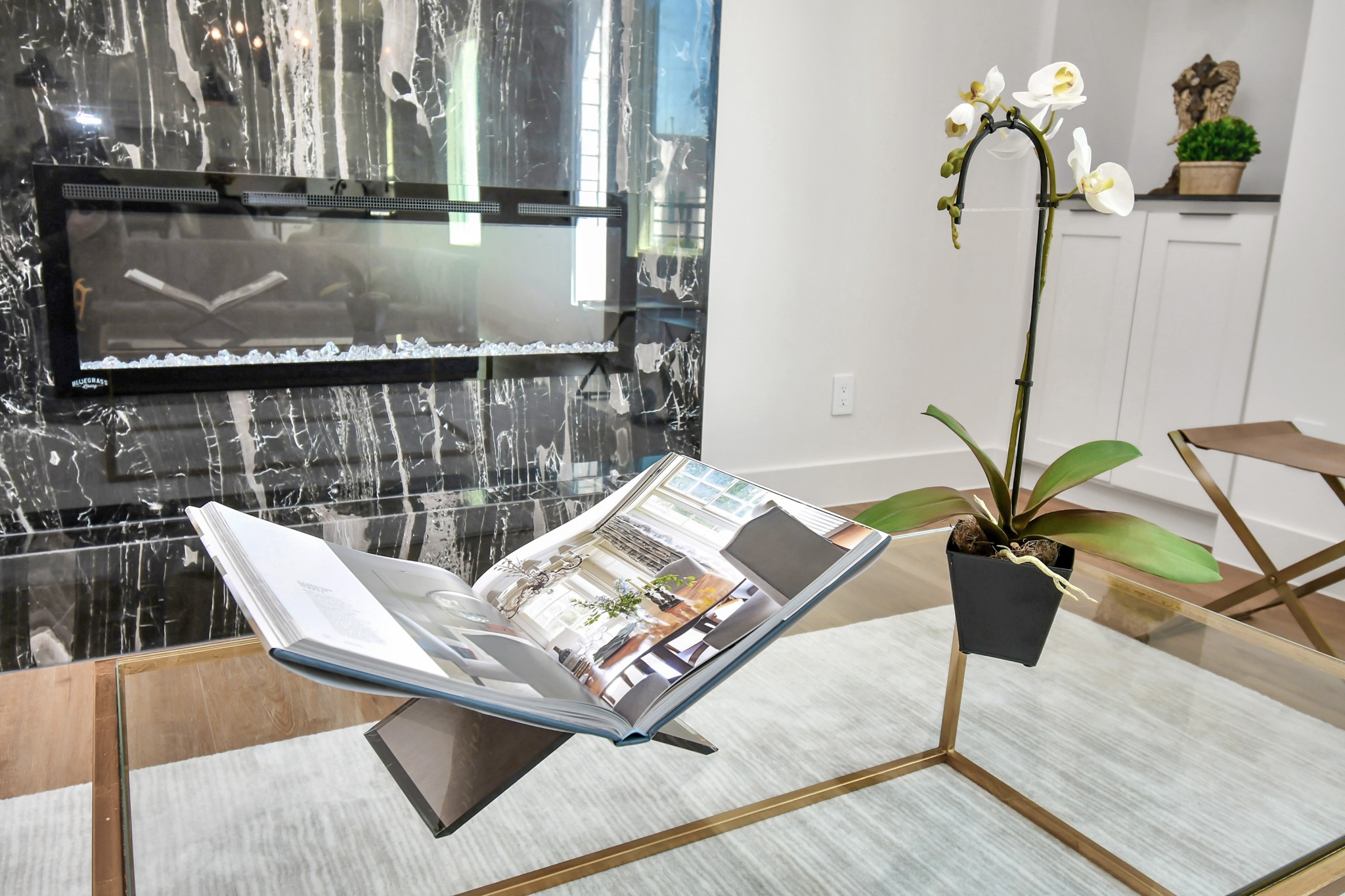 2512 Gray Street Houston, TX 77003 - Photo 14 of 46 This modern living area features a sleek, black marble fireplace, a glass-top coffee table with a decorative book, and a potted orchid, creating an elegant and inviting atmosphere.