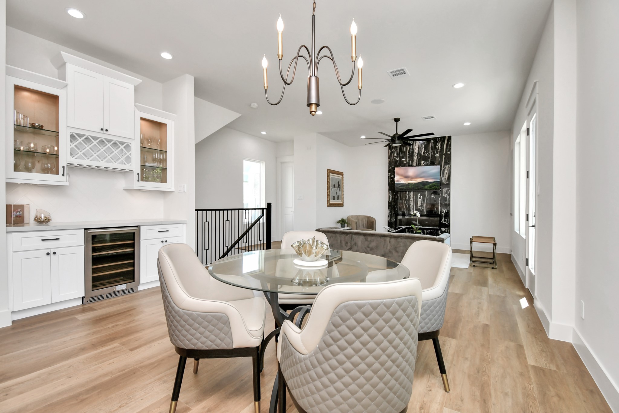 2512 Gray Street Houston, TX 77003 - Photo 16 of 46 This modern, open-concept living area features a stylish dining space with a glass table and upholstered chairs, a chic light fixture, and a wet bar with a wine cooler. The cozy living room offers a sleek, contemporary fireplace and ample natural light, perfect for entertaining.