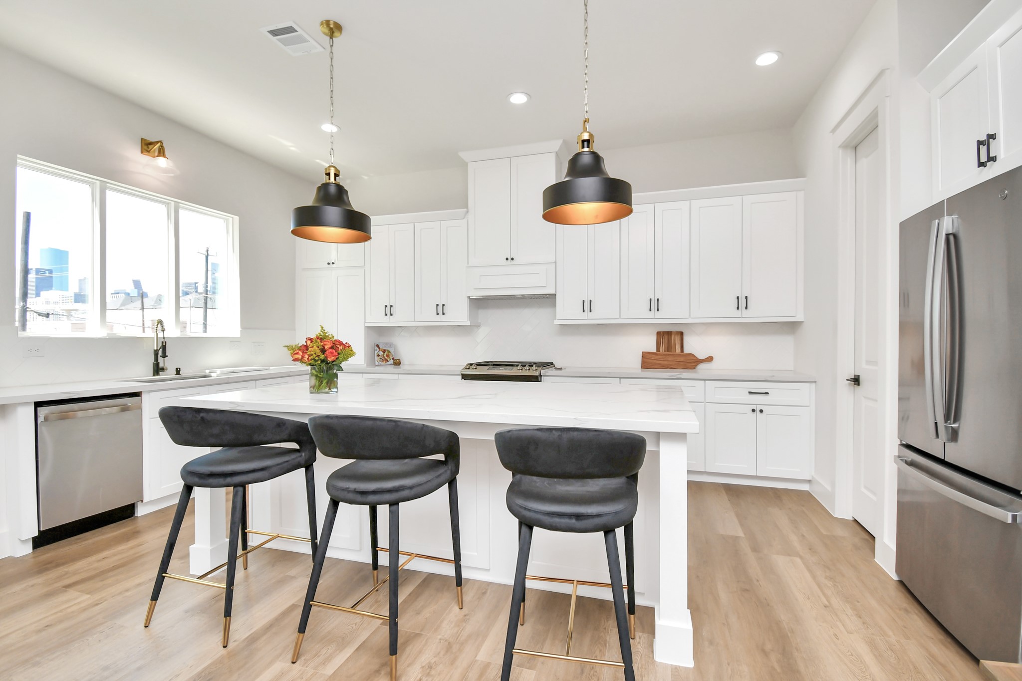2512 Gray Street Houston, TX 77003 - Photo 19 of 46 This modern kitchen features sleek white cabinetry, a spacious island with seating for three, and stylish pendant lighting. Stainless steel appliances and ample natural light create a bright, inviting atmosphere.
