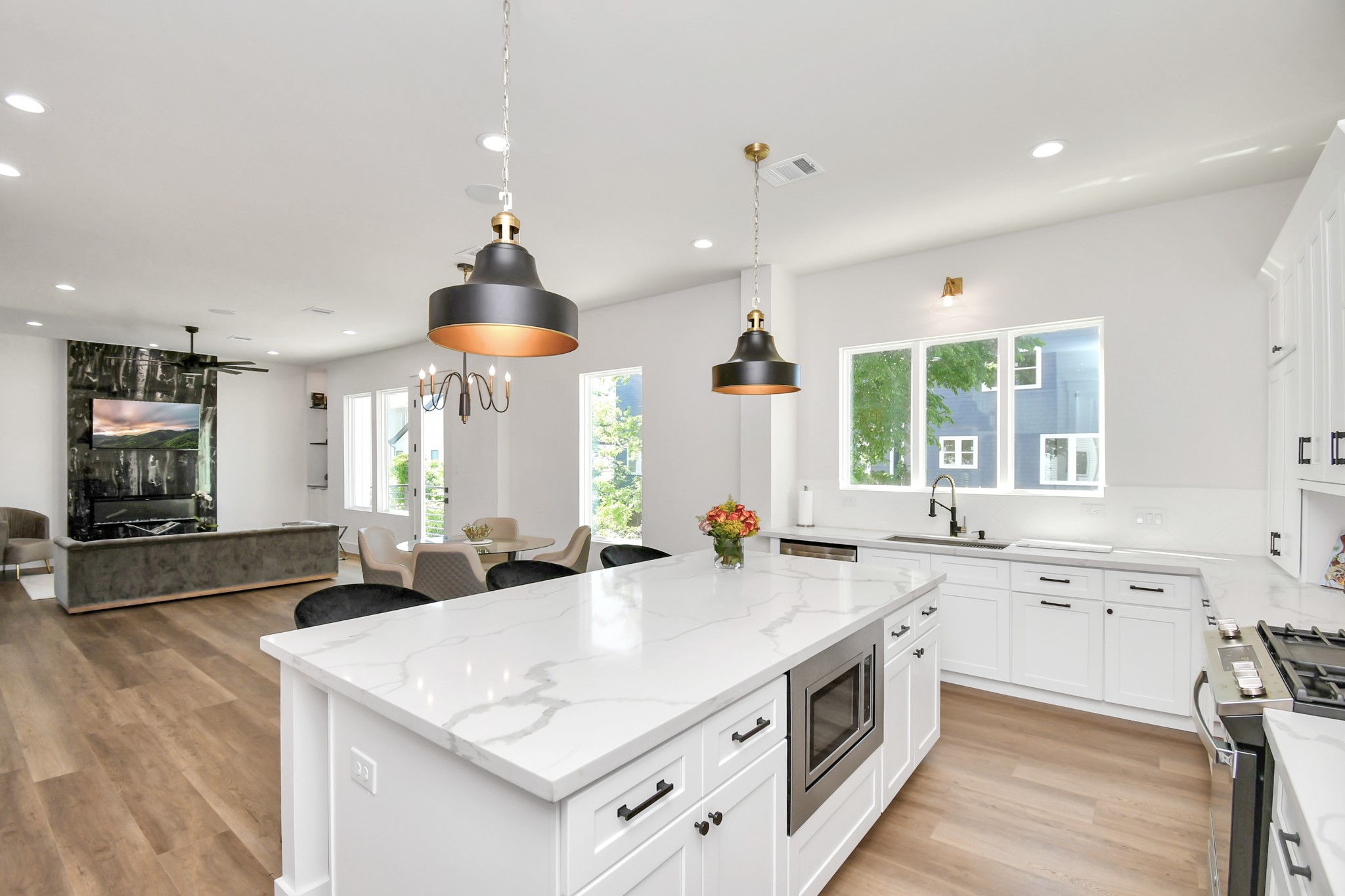 2512 Gray Street Houston, TX 77003 - Photo 20 of 46 This modern kitchen features a spacious open layout with a large island, white cabinetry, and sleek appliances. It flows seamlessly into a bright living area with large windows and stylish lighting, perfect for entertaining.