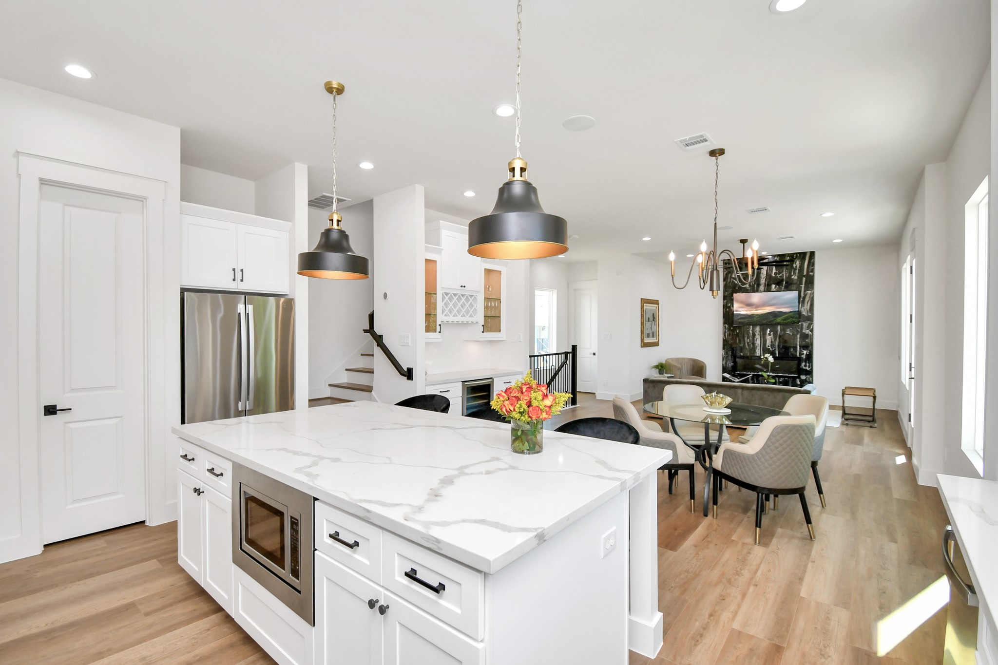 2512 Gray Street Houston, TX 77003 - Photo 22 of 46 This open-concept living space features a modern kitchen with a large marble island, stainless steel appliances, and elegant pendant lighting. The adjoining dining and living areas boast wood flooring, a stylish chandelier, and a cozy fireplace, creating a welcoming atmosphere.