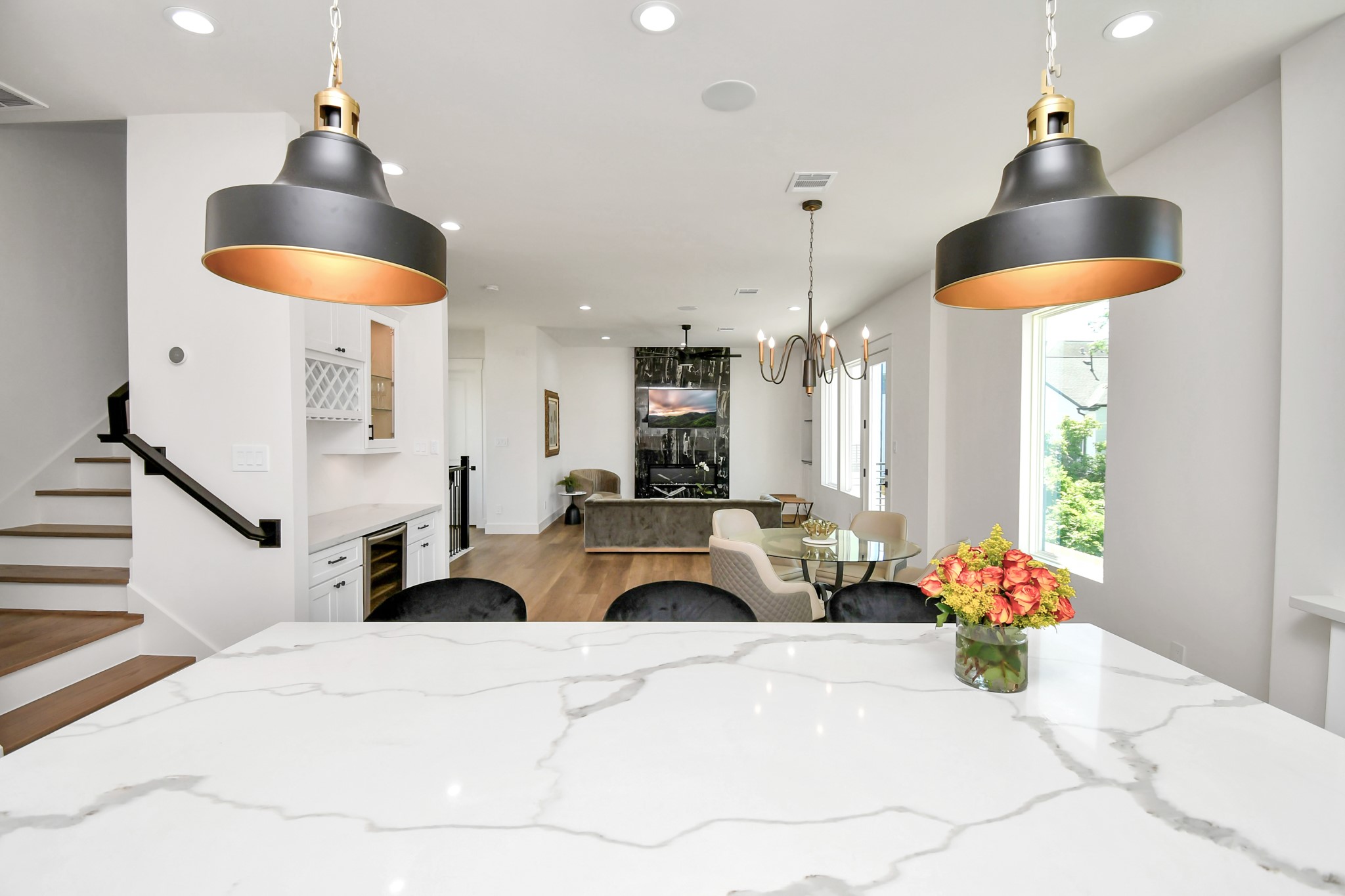2512 Gray Street Houston, TX 77003 - Photo 24 of 46 Stylish open-concept kitchen and living area with elegant marble countertops, modern pendant lighting, and a cozy seating area. The space is bright and airy, featuring a staircase, built-in wine rack, and a view of the outdoors through large windows.