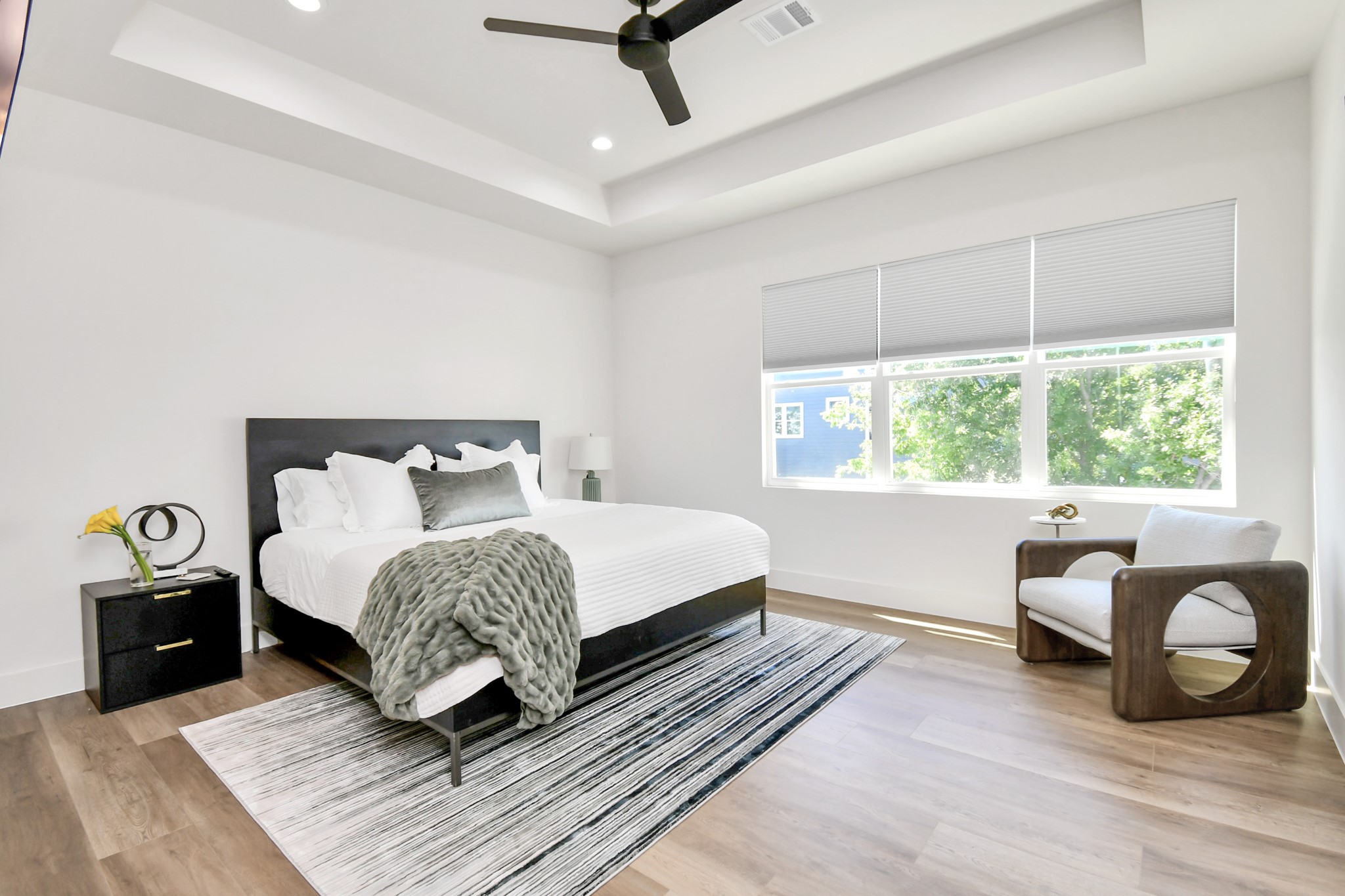 2512 Gray Street Houston, TX 77003 - Photo 25 of 46 This bedroom features a spacious and modern design with a large window providing ample natural light. It includes a stylish ceiling fan, wooden flooring, and a cozy seating area. The room is elegantly furnished with a comfortable bed and minimalistic decor.