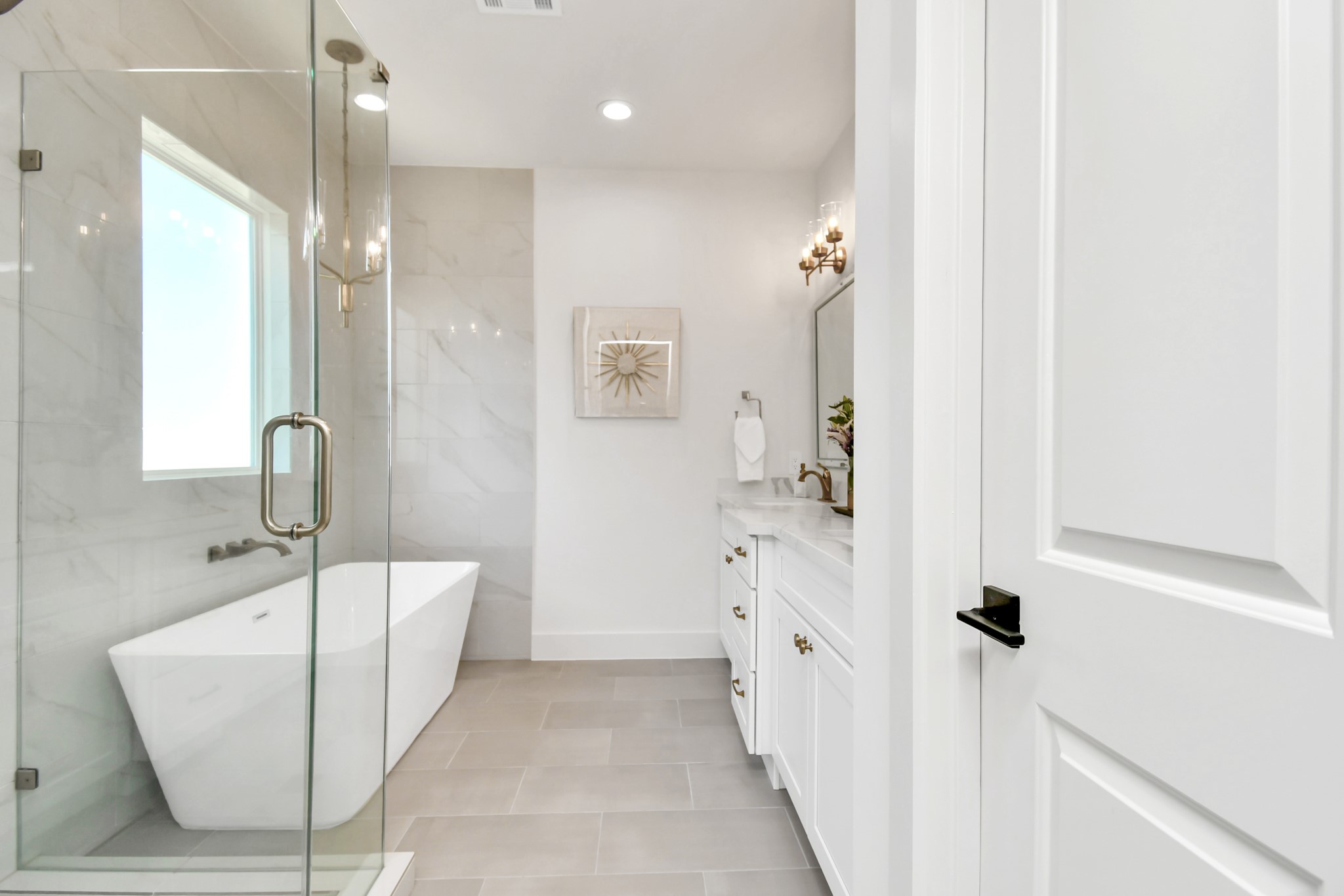 2512 Gray Street Houston, TX 77003 - Photo 30 of 46 This bathroom features a modern design with a glass-enclosed shower, a freestanding tub, and elegant fixtures. White cabinetry and neutral tiles create a bright and spacious atmosphere.