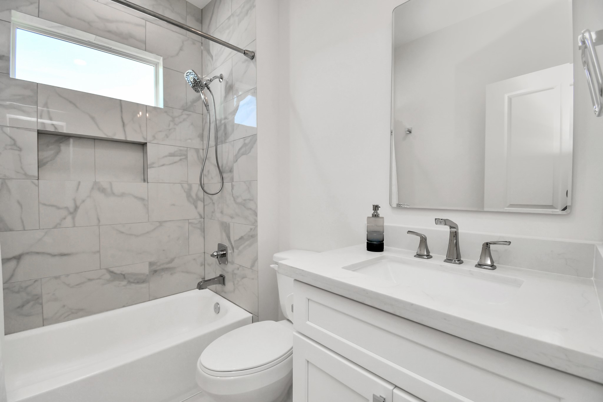 2512 Gray Street Houston, TX 77003 - Photo 37 of 46 Modern bathroom featuring a sleek vanity with dual faucets, a large mirror, and a tub-shower combo with elegant marble-style tiling. Bright and airy with a minimalist design.