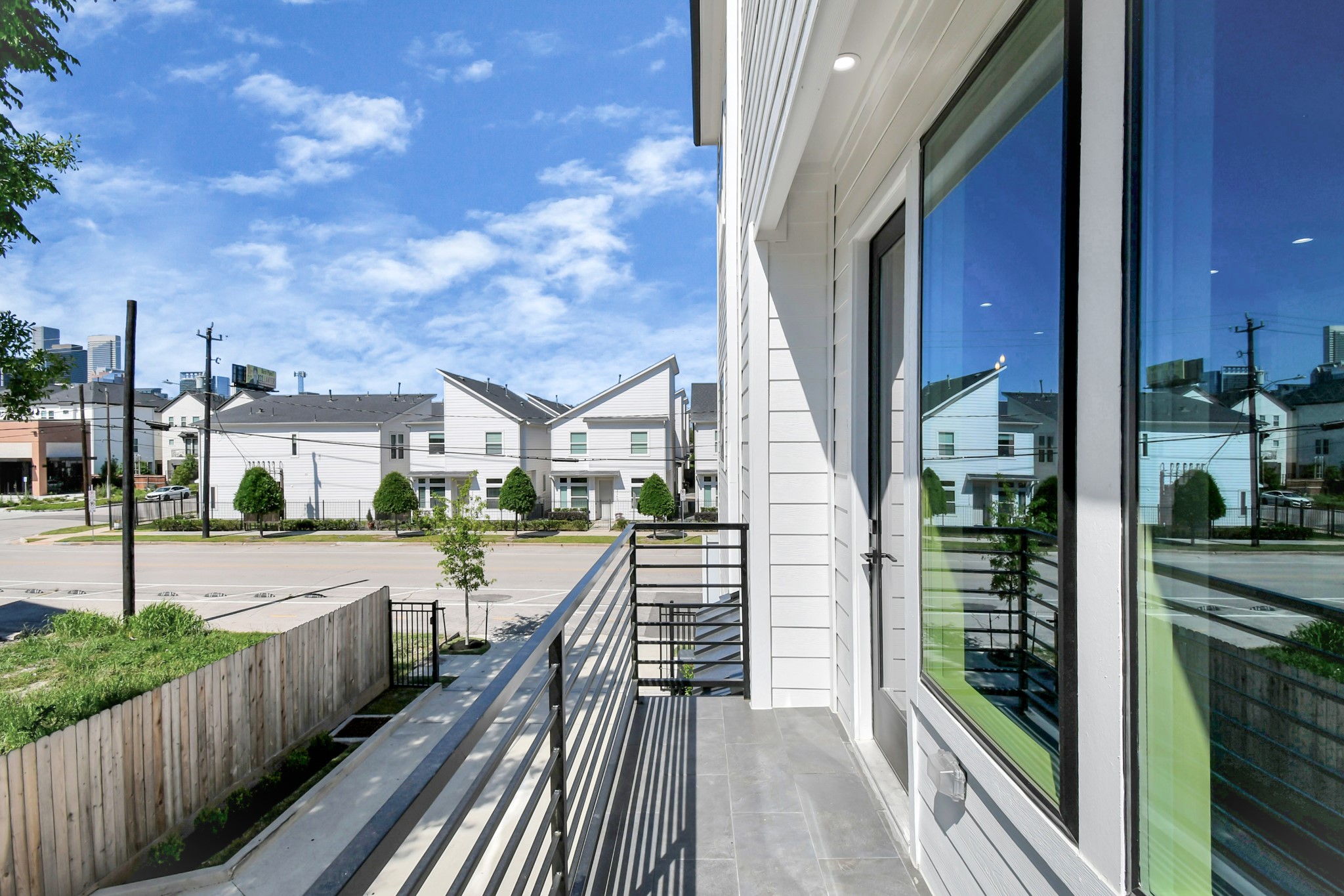2512 Gray Street Houston, TX 77003 - Photo 39 of 46 This photo shows a modern balcony with sleek railings overlooking a suburban street. Nearby are contemporary homes with well-maintained landscaping. Large windows suggest bright interiors.