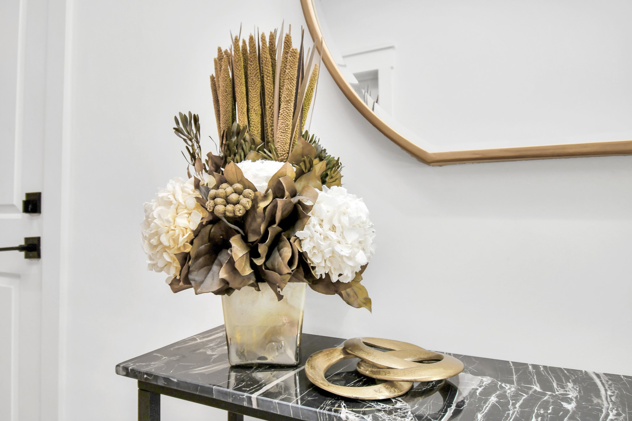 2512 Gray Street Houston, TX 77003 - Photo 40 of 46 This photo showcases a stylish entryway with a black marble table, featuring a decorative floral arrangement in a square vase and a modern gold decorative piece, set against a neutral wall with a partial view of a round mirror.