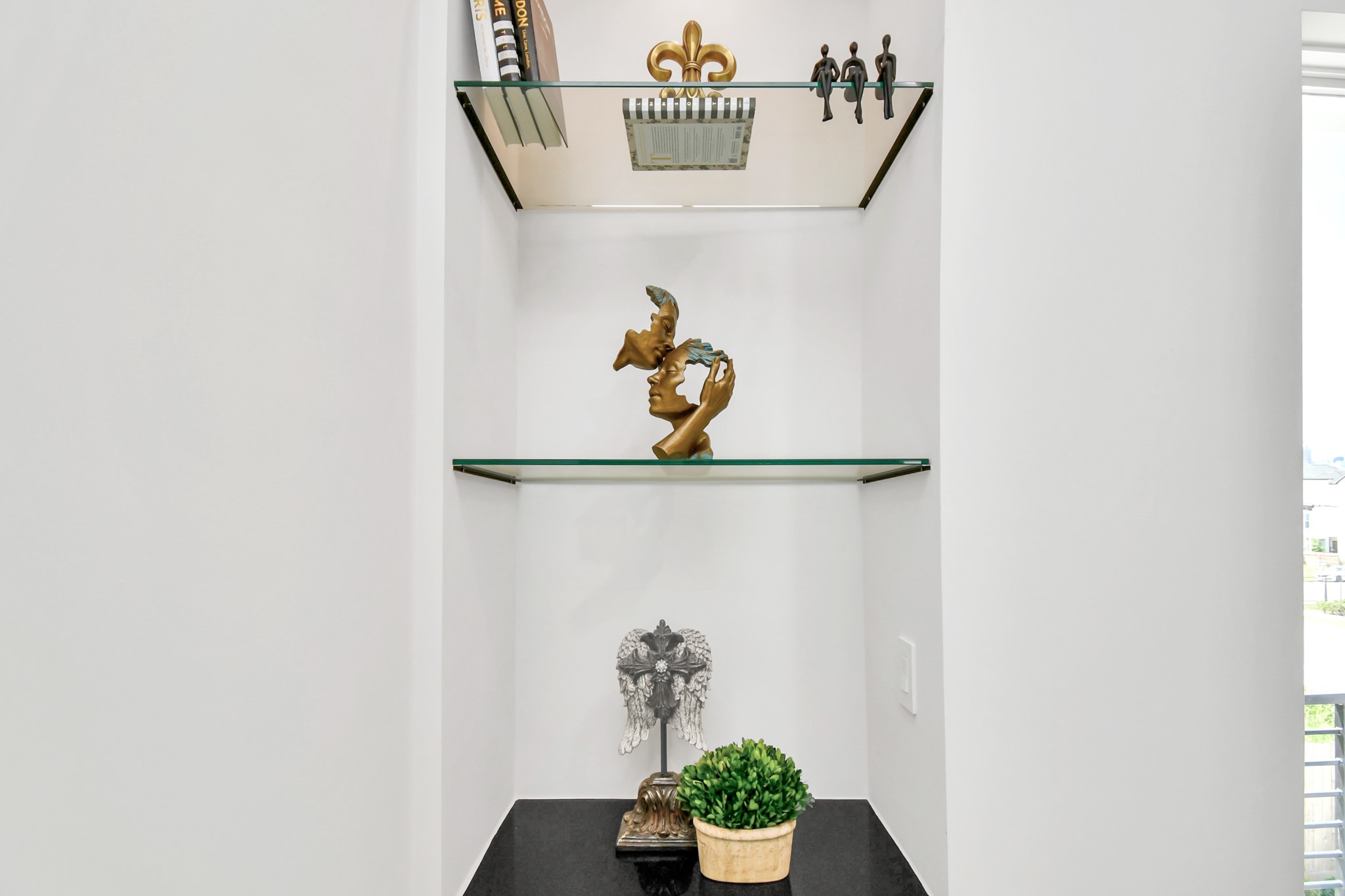 2512 Gray Street Houston, TX 77003 - Photo 41 of 46 This photo features a modern, built-in niche with glass shelves displaying decorative items, including sculptures and books. The space is well-lit and adds a stylish touch to the home's interior.