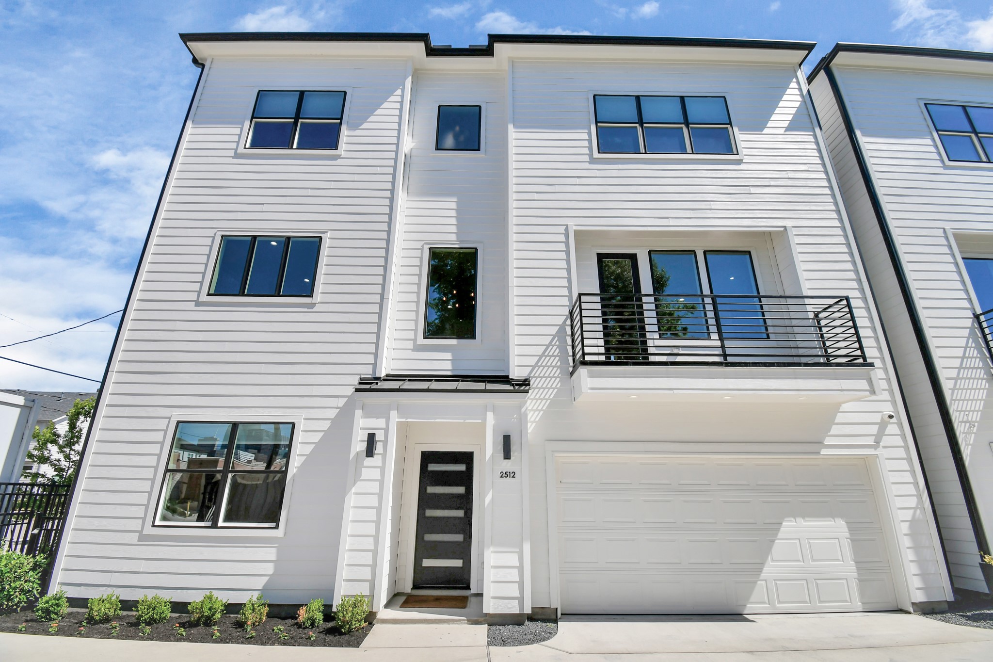 2512 Gray Street Houston, TX 77003 - Photo 43 of 46 This modern, three-story townhouse features a sleek white exterior, large windows for natural light, and a balcony. It includes a two-car garage and a minimalistic front garden, offering a contemporary and stylish living space.