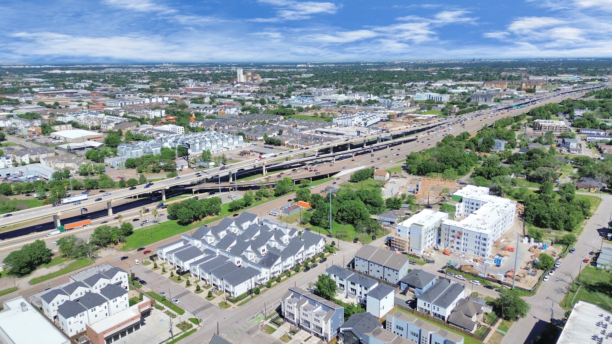 2512 Gray Street Houston, TX 77003 - Photo 45 of 46 The photo showcases a suburban area with modern townhouses and apartment buildings, situated near a major highway, offering convenient access to urban amenities. The neighborhood is green with plenty of trees, providing a blend of city and suburban living.
